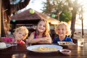 Three happy children enjoying dinner outdoors at a beachside restaurant in North Myrtle Beach near Sea House Villas.